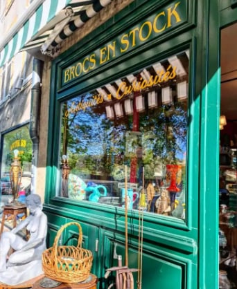 La vitrine « Antiquités · Curiosités » en lettres dorées, une statue blanche devant